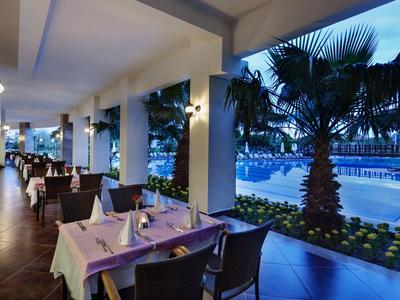 Moderner Außenbereich eines Restaurants mit gedeckten Tischen und Blick auf beleuchteten Pool.