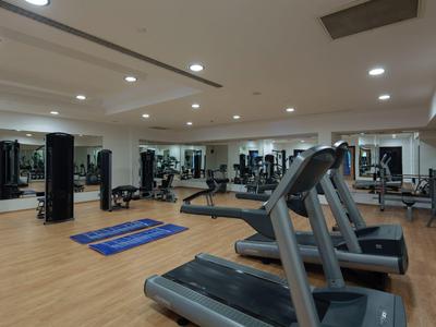 Großer, heller Fitnessraum mit Laufbändern, Hanteln, Spiegeln und blauen Trainingsmatten.