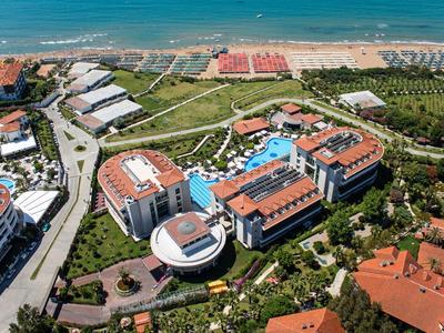 Große Hotelanlage mit mehreren Gebäuden, Pools und Strand in Meeresnähe, grünen Gärten umgeben.