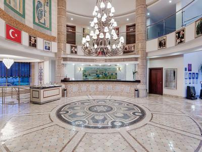 Grande hall d'hotel con pavimento in marmo, lampadario e reception.