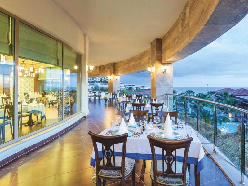 Terras met buitentafels met uitzicht op stad en rivier bij schemerlicht.