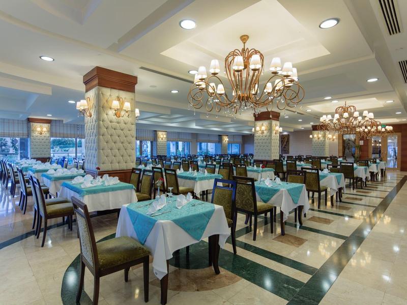 Groot, elegant hotelrestaurant met tafelkleden en kroonluchters.