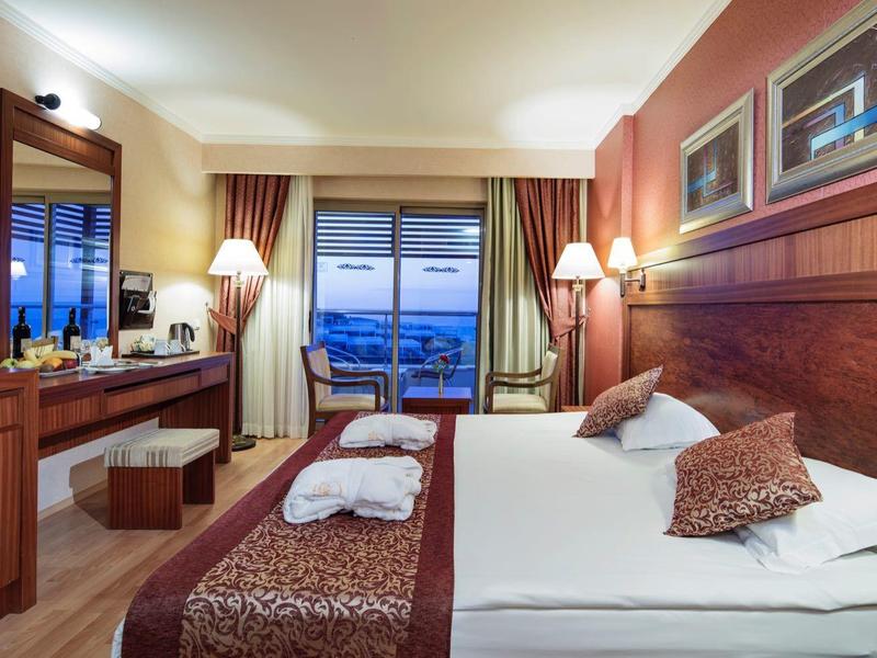 Gezellige hotelkamer met tweepersoonsbed, bureau, tv en balkon met uitzicht op zee.