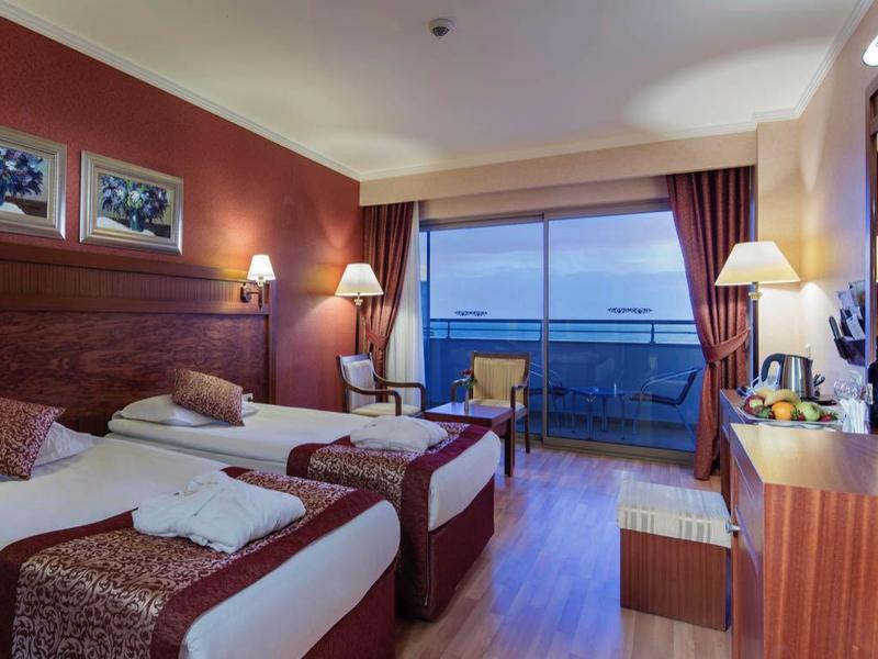 Moderne hotelkamer met twee bedden, houten wanden, groot raam met zeezicht en een bureau.