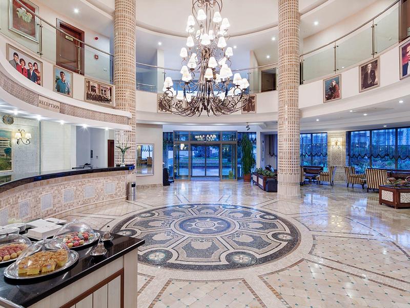 Luxe hotelhal met marmeren vloer, kroonluchter en buffetgedeelte.