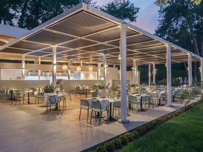 Open restaurant area with tables and chairs under a covered pavilion at dusk.