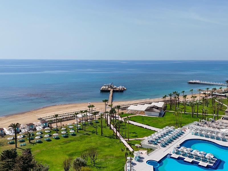 Beach resort with large pool, lounge areas, palm trees, and direct sea access