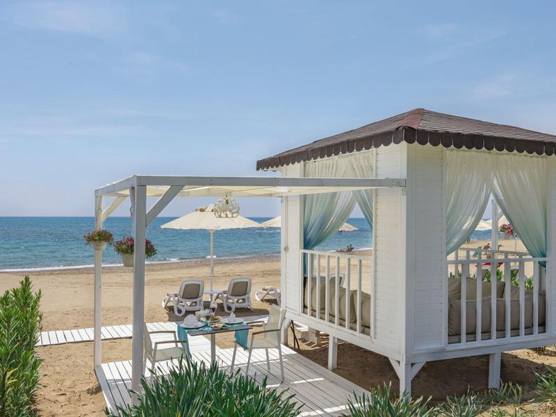 Beach with pavilion and seating area overlooking the sea under clear sky.