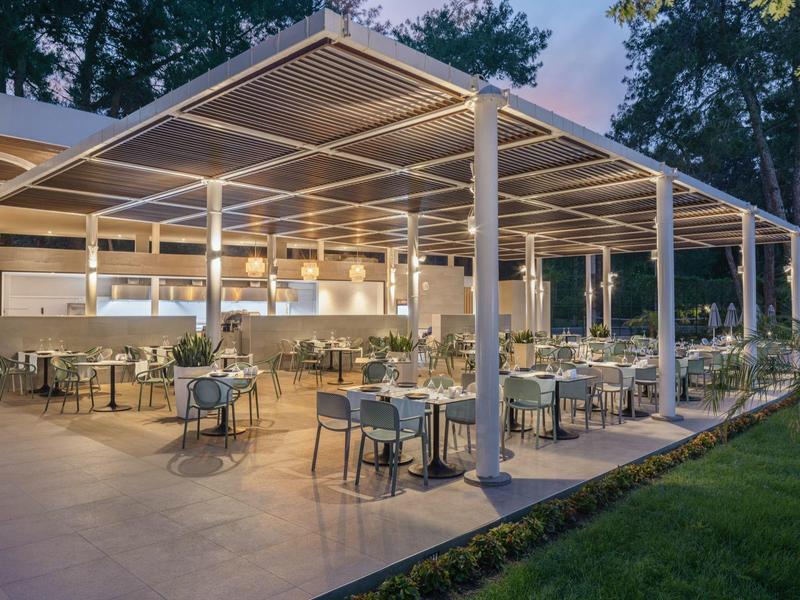 Modern covered outdoor restaurant area with stylish tables and chairs at dusk.