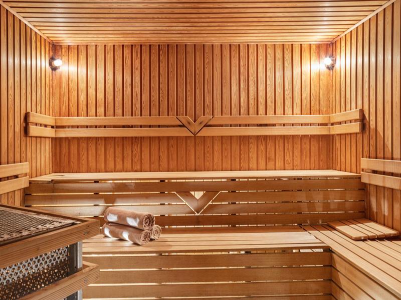 Wooden sauna with benches and two wall lights in a hotel sauna