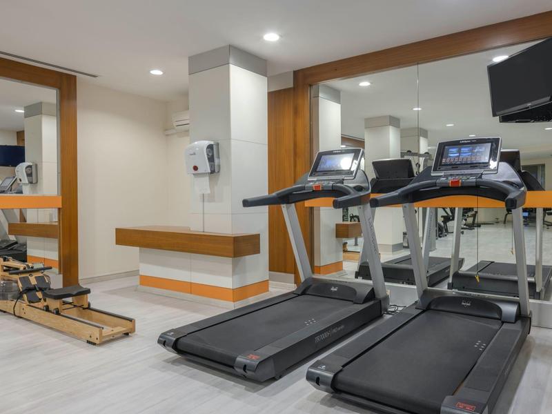 Modern gym with treadmills, mirrored wall, and wooden accents.