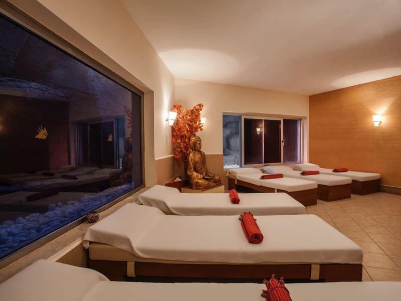 Relaxation room with multiple loungers and soft lighting, decorated with plants.