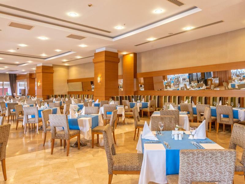 Prostorná restaurace s prostřenými stoly a modro-bílými ubrusy.