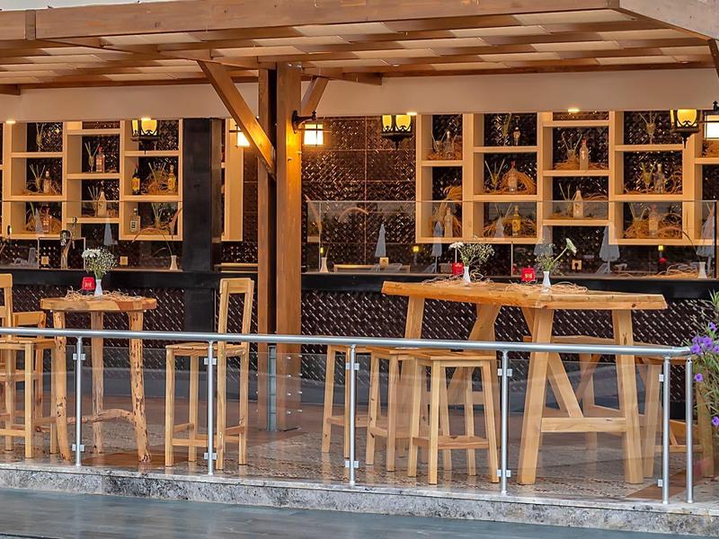 Pohodlný venkovní bar s dřevěnými stoličkami a teplým osvětlením večer.