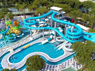 Large water park with blue tube slides and multiple pools surrounded by green trees.