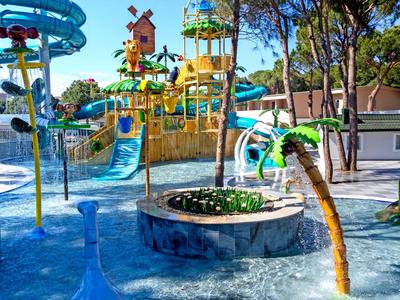 Colorful water park with slides and play structures under blue sky and trees.