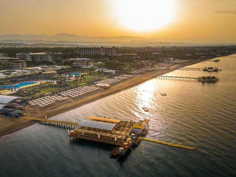 Sonnenuntergang über Küste mit Hafen, Stegen, Hafenanlagen und ruhigem Meerwasser.