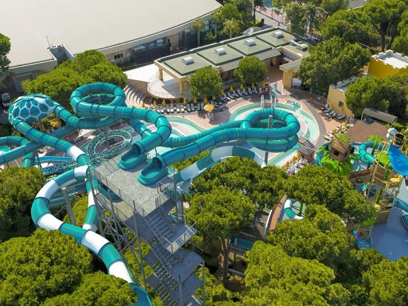 Luftaufnahme eines Wasserparks mit großen Rutschen umgeben von Bäumen.