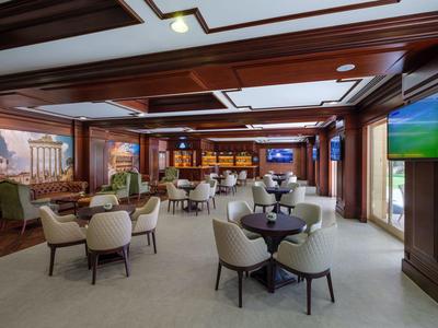 Eleganter Hotel-Loungebereich mit Sesseln, Tischen und großem Fenster mit Blick nach draußen.