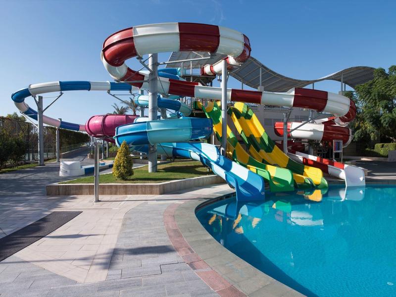 Bunte Wasserrutschen mit Kurven am Poolrand in einem Outdoor-Wasserpark.