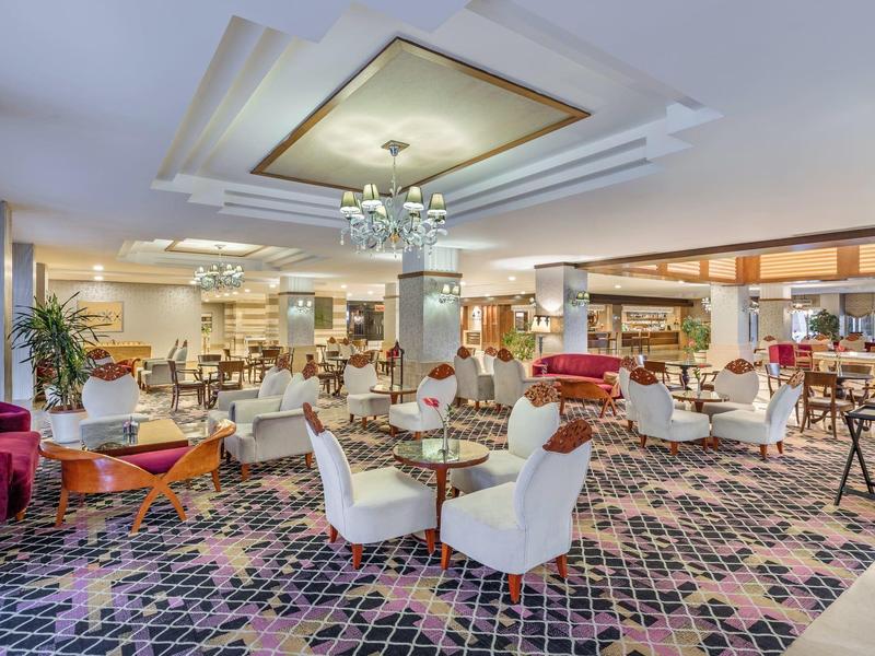 Elegantes Hotelrestaurant mit gemütlichen Sesseln, modernen Lampen und Teppichboden.