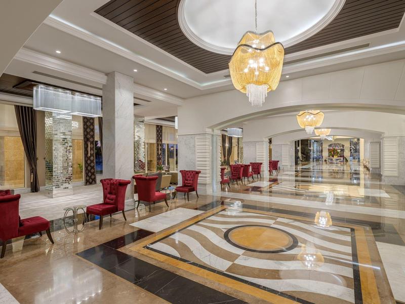 Elegante Hotellobby mit Marmorboden, roten Sesseln und dekorativem Kronleuchter