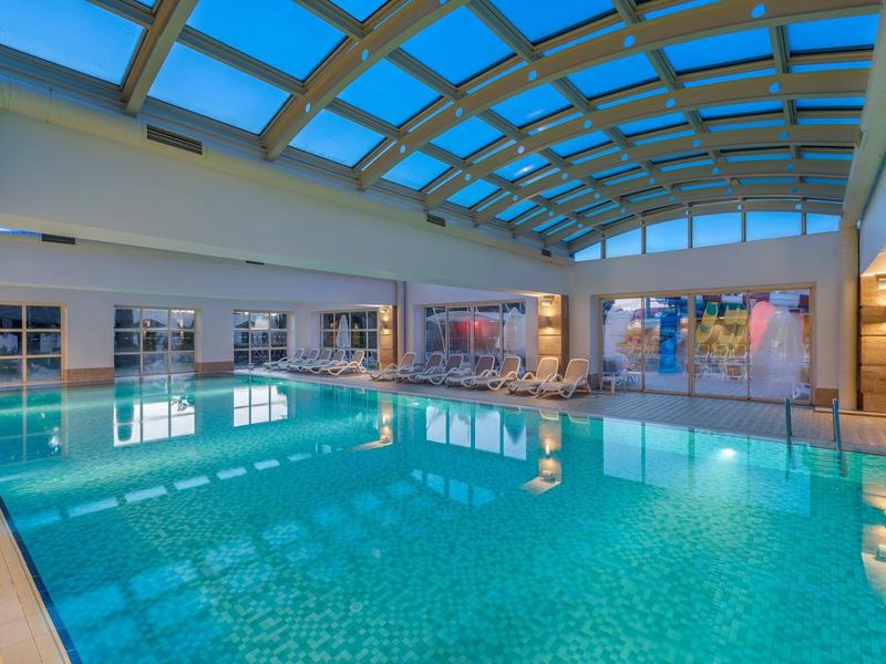 Innenpool mit Glasdach und modernen Sitzelementen in einem Hotel.