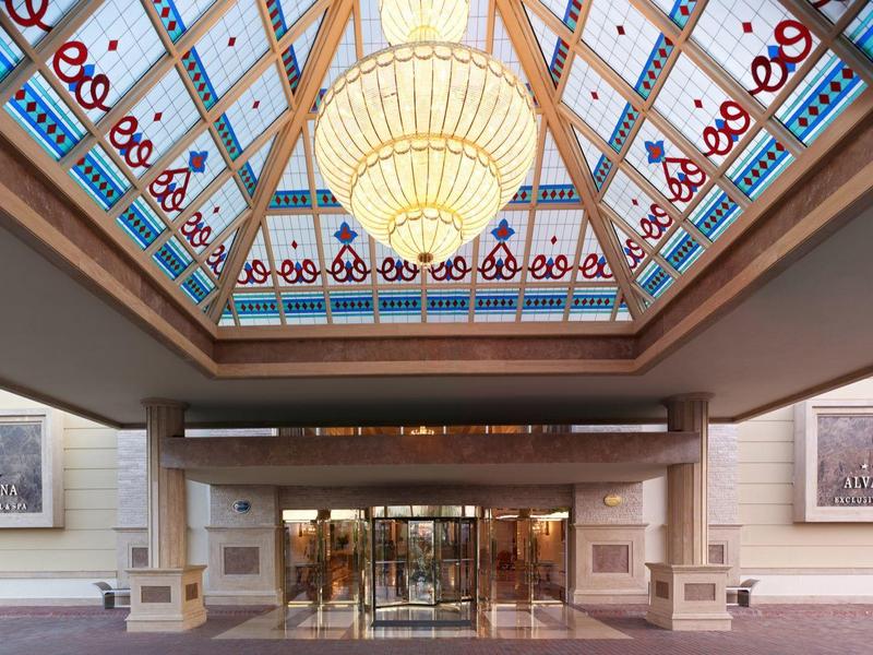 Hotel-Eingang mit glasüberdachtem Atrium und großen Kronleuchtern