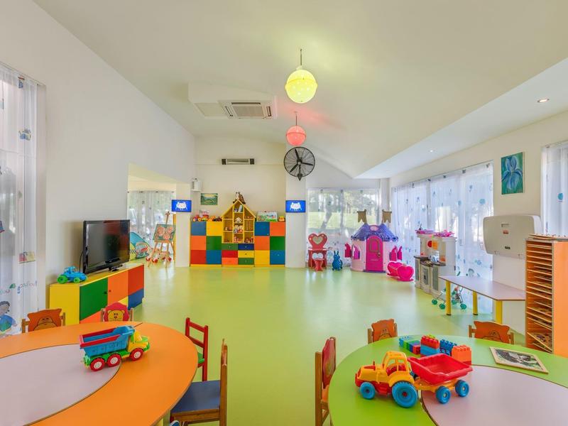 Bunter Spielraum mit Spielzeug, Tischen und Stühlen in hellem, modernen Kinderbereich.