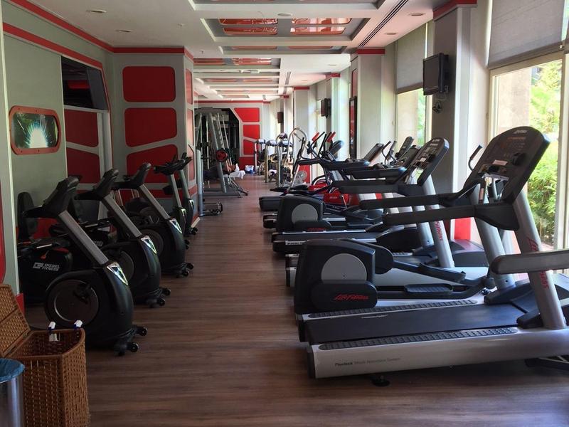 Intérieur d'une salle de sport moderne avec tapis de course et équipements d'exercice près de grandes fenêtres.