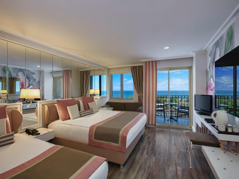 Chambre d'hôtel moderne avec deux lits doubles, télévision par satellite et balcon avec vue sur la mer.