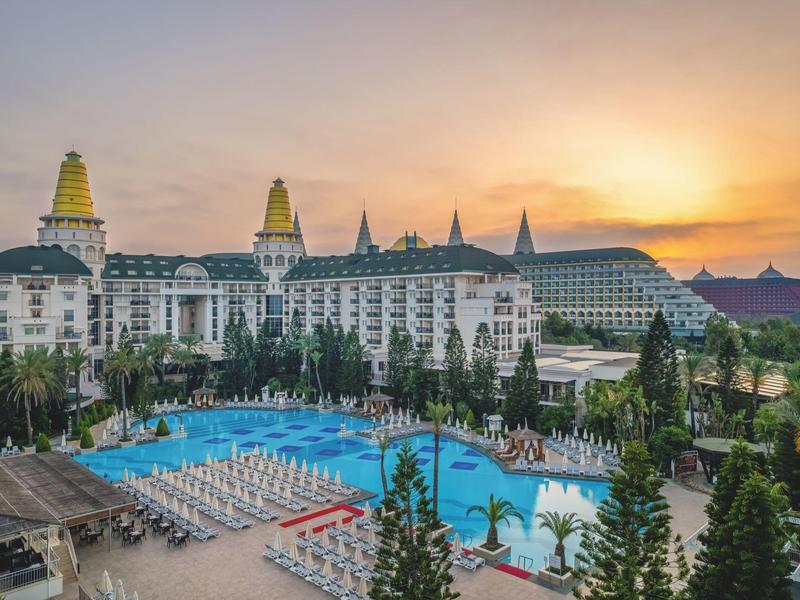 Grand complexe hôtelier avec piscine bleue et coucher de soleil en arrière-plan