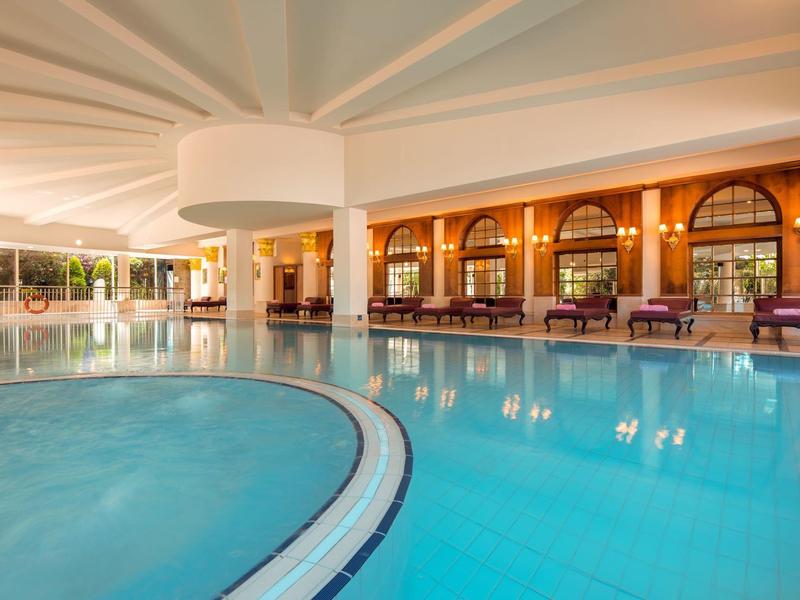 Grand bassin intérieur avec colonnes rondes et espaces de détente confortables dans un hôtel de luxe.