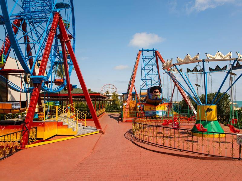 Parc d'attractions coloré avec manèges, grande roue et temps clair.
