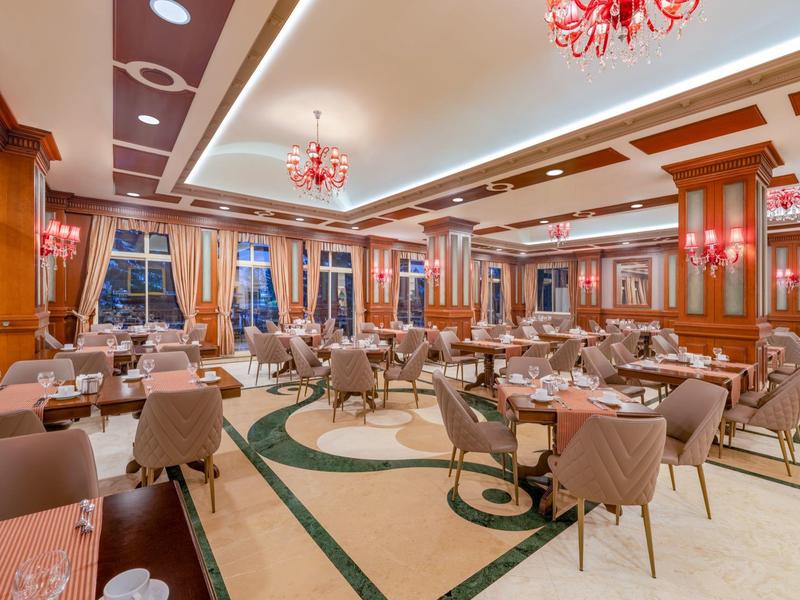 Grande salle à manger d'hôtel avec tables dressées, chaises confortables et design élégant.