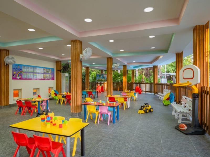 Espace de jeu intérieur coloré avec tables, chaises et jouets dans un cadre hôtelier.