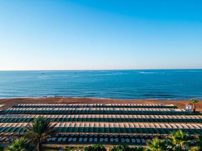 Strand mit Sonnenschirmen und Liegen am Meer, klarer Himmel, ideal für Urlaub und Entspannung.