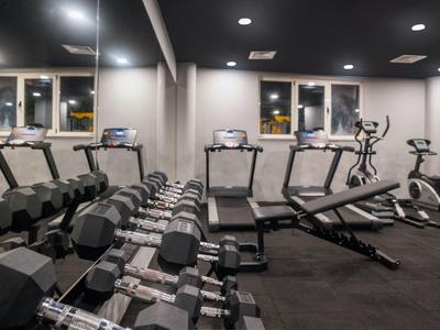 Fitnessraum mit Hanteln, Laufbändern und einem Rudergerät in einem Hotel.