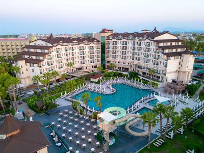 Großes Resort-Hotel mit geschwungenem Pool, Wasserrutschen und Sonnenschirmen in tropischer Umgebung.