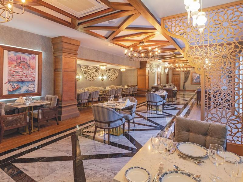 Sala de comedor elegante con diseño artístico del techo y mobiliario cómodo en tonos cálidos.