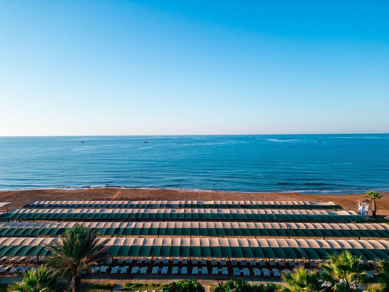 Vista de una larga playa de arena con sombrillas y el mar azul al fondo