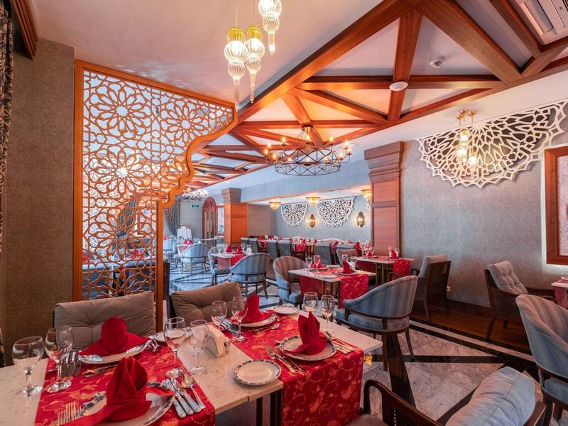 Restaurante elegante con manteles rojos, sillas modernas y estructura decorativa de madera en el techo.