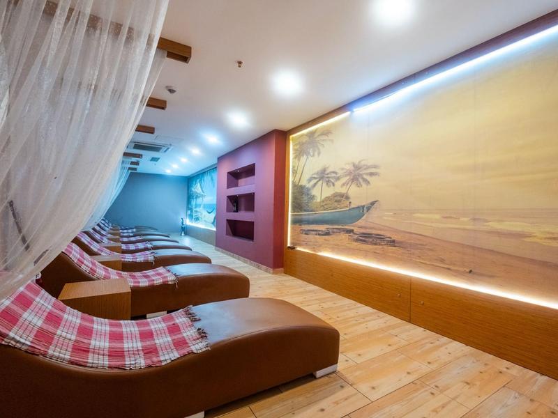 Sala de descanso con tumbonas y luz tenue, decorada con un mural de paisaje tropical.