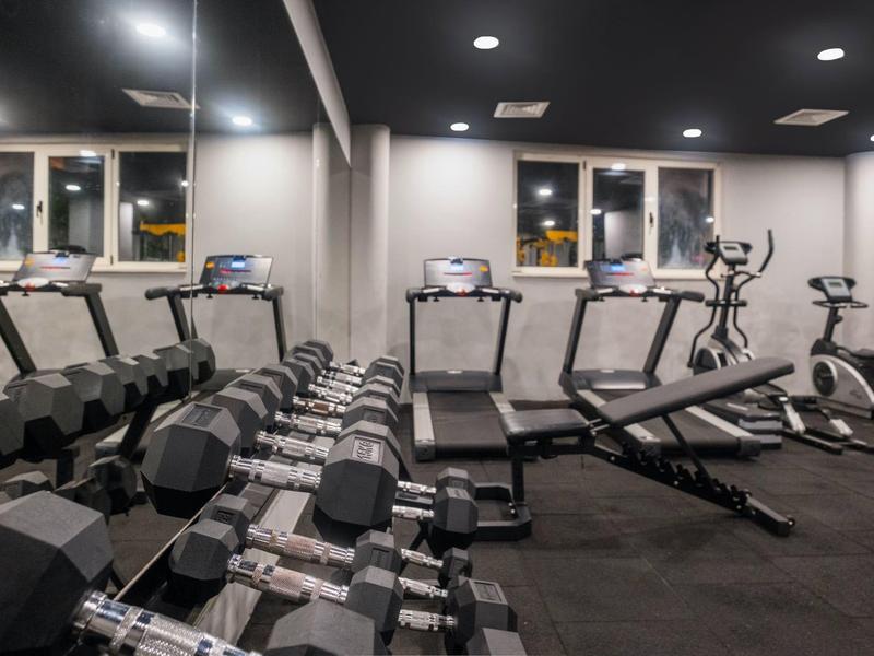 Gimnasio con pesas, cintas de correr y equipos de entrenamiento en un hotel.