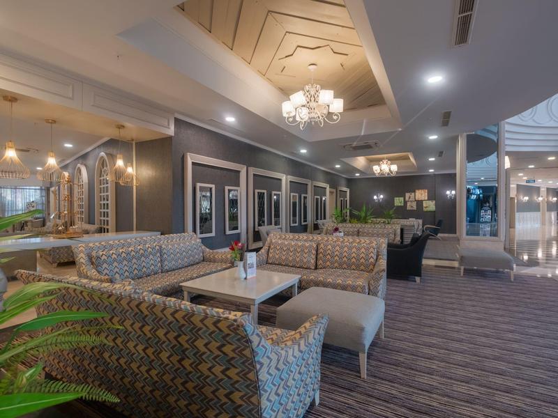 Lobby espaciosa del hotel con áreas de asiento, sillones acolchados, mesas y iluminación elegante.