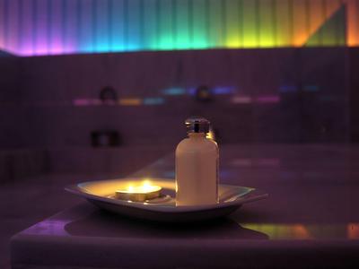 Świeca na białym talerzu w klimatycznie oświetlonym spa.