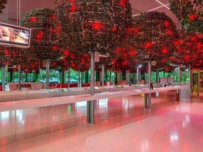 Moderne binnenruimte met rode boominstallaties en lange banken in een hotel.