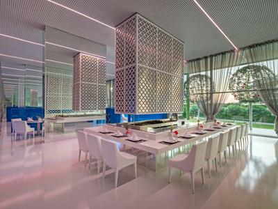 Moderne eetkamer met een grote tafel, witte stoelen en grote ramen met uitzicht op groen.