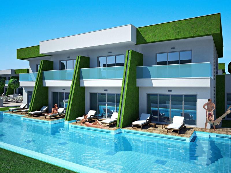 Modern hotel met groene accenten, groot zwembad, ligstoelen en balkons bij elke kamer.