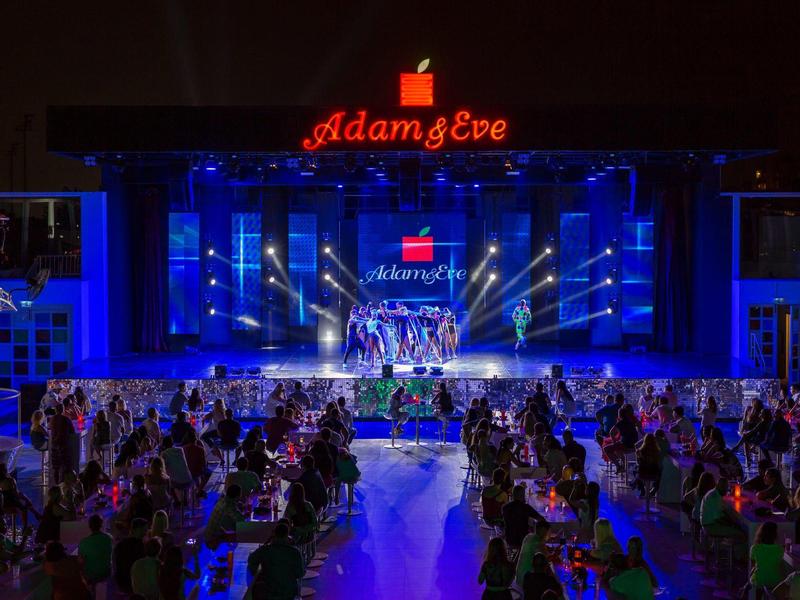 Buitenavond evenement met podium, blauw licht en publiek aan tafels